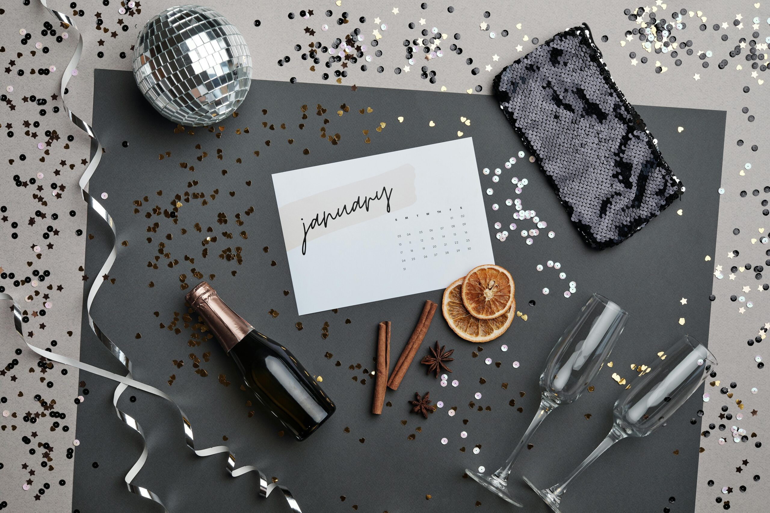 Festive New Year party scene with champagne, calendar, and decorations in a flat lay format.