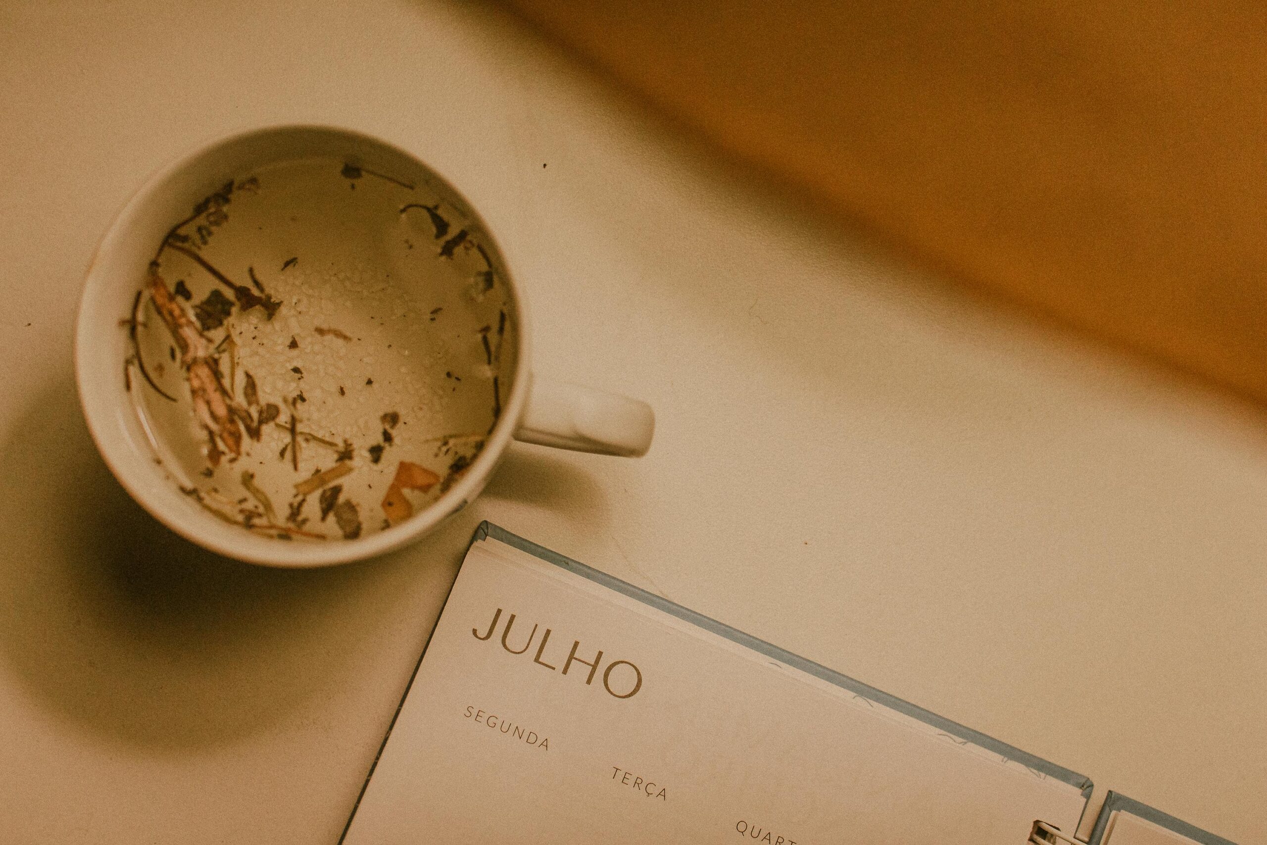 Top view of a herbal tea cup beside a July calendar page, evoking calm and planning.