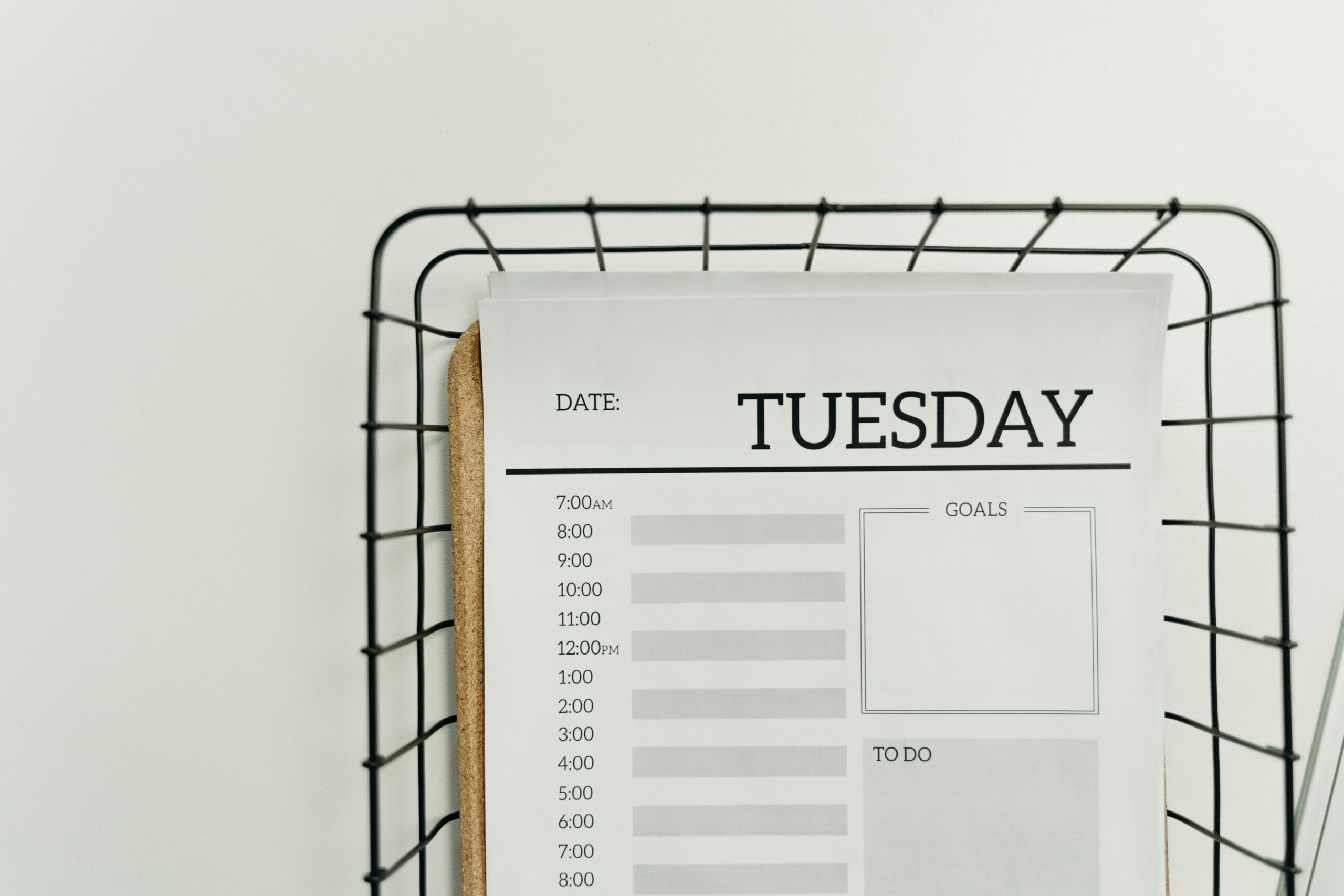 Top view of a minimalist Tuesday planner on a wire basket for organization and scheduling.