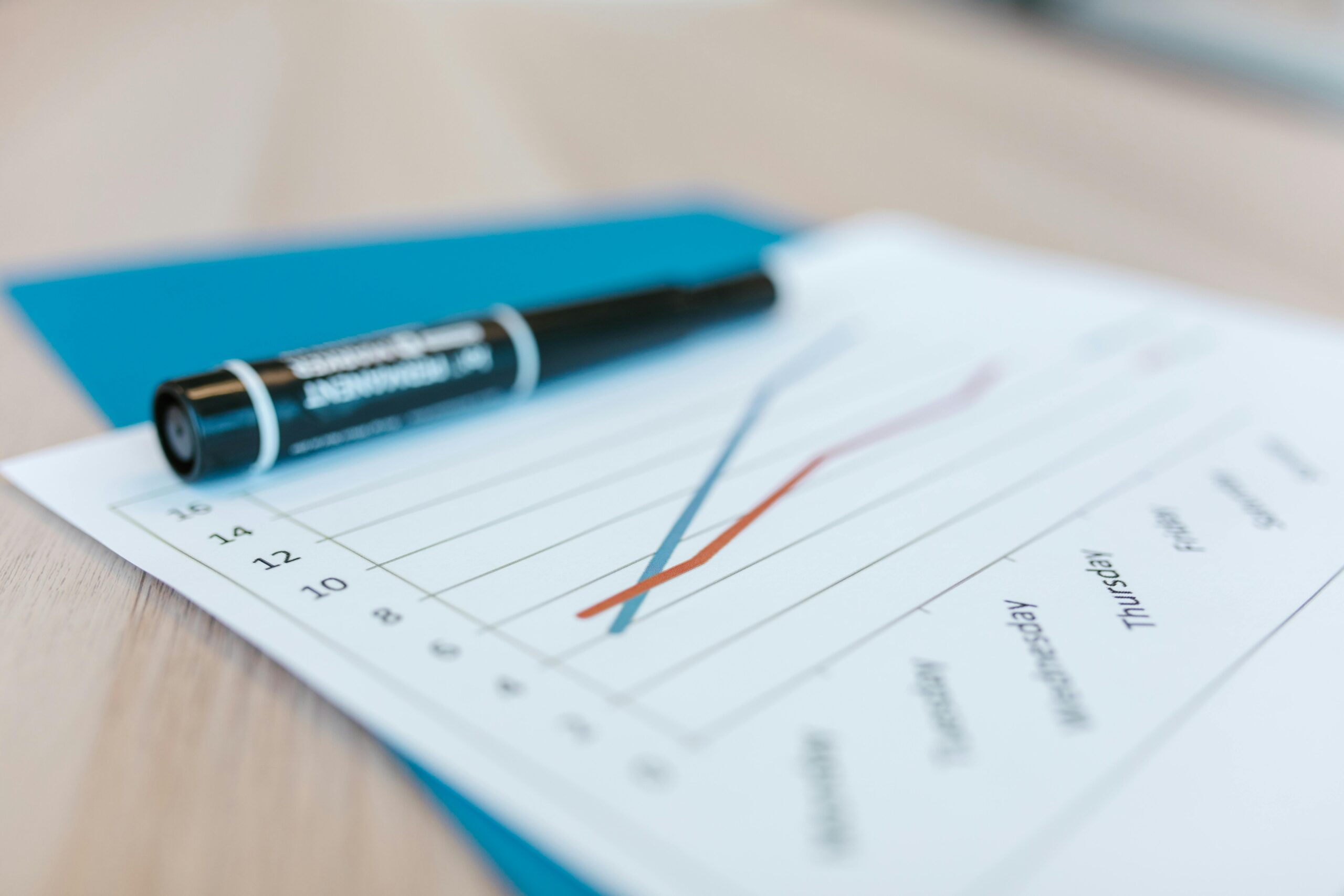 Dynamic line chart on paper with black marker on a desk, illustrating data trends.