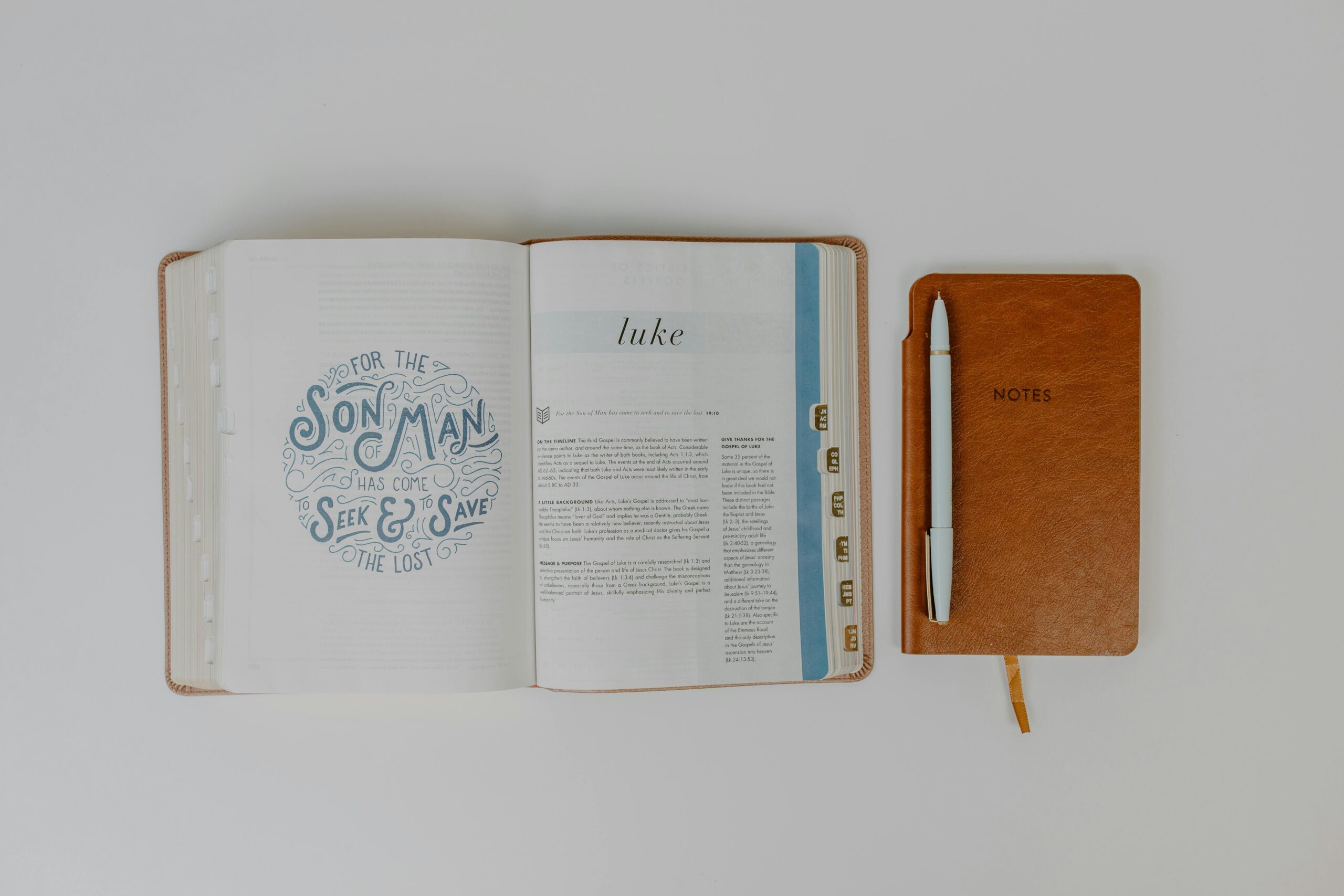 Flat lay of an open Bible next to a notebook and pen, ideal for faith and study themes.