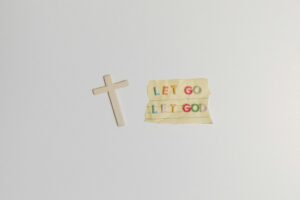 A simple and powerful image featuring a cross alongside the inspiring quote 'Let Go Let God' on paper.