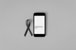 Black ribbon and smartphone with inspiring message for cancer awareness campaigns.